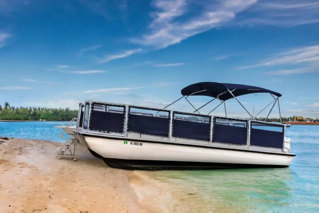 Beachcat 26x10 commercial pontoon boat beached with reinforced hull and Bimini top