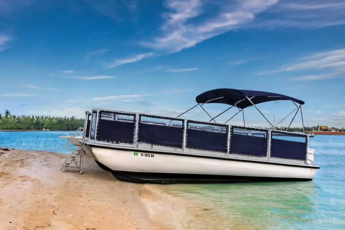 Beachcat 26x10 commercial pontoon boat beached with reinforced hull and Bimini top